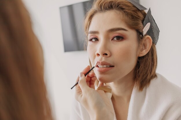 Photo makeup artist is applying lipstick to the clients