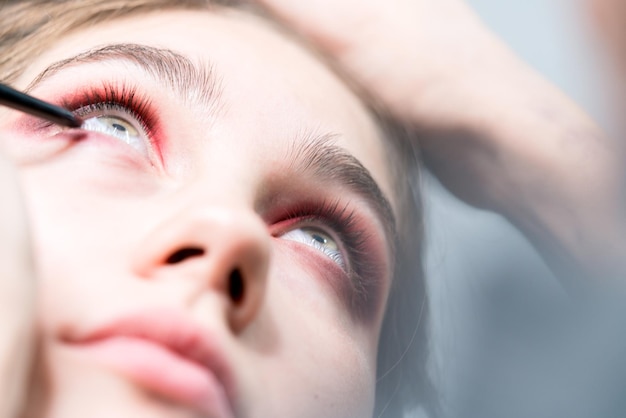 Makeup artist performs bright eye makeup Eyeliner pencil Closeup