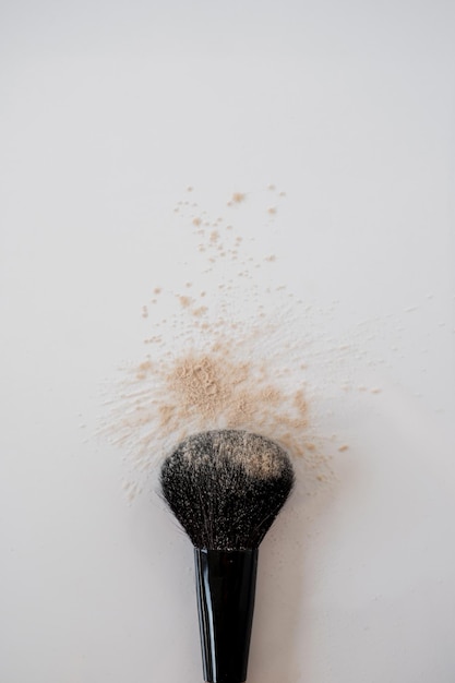 Photo makeup brush and beige cosmetic powder scattered on white background aesthetic beauty product sample concept flat lay top view