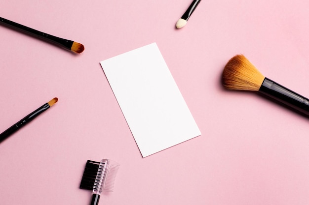 Makeup brush and white business card on pink background a horizontal template for a makeup artists b