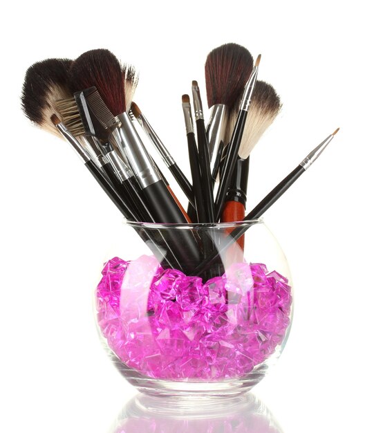 Makeup brushes in a bowl with stones isolated on white