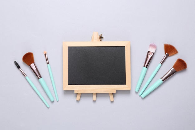 Makeup brushes and chalk board on a white background Copy space