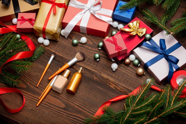 Makeup brushes and other cosmetics near Christmas gifts on a table