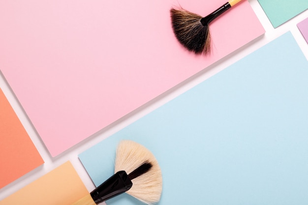 Makeup brushes on pastel colored paper, top view