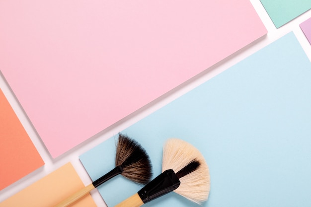 Makeup brushes on pastel colored paper, top view