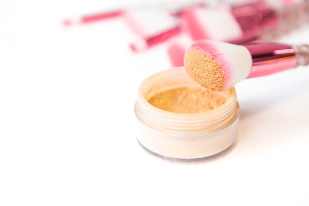 Makeup brushes and powder on a white background. Selective focus.