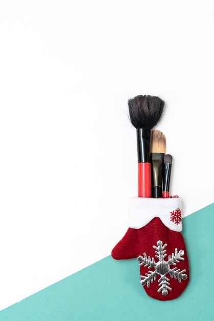 Makeup brushes in the red mitten of Santa Claus. Close-up. Christmas parties and New Year themes.