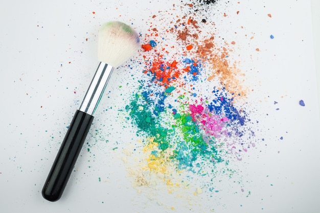 Photo makeup brushes on white background with colorful pigment powder