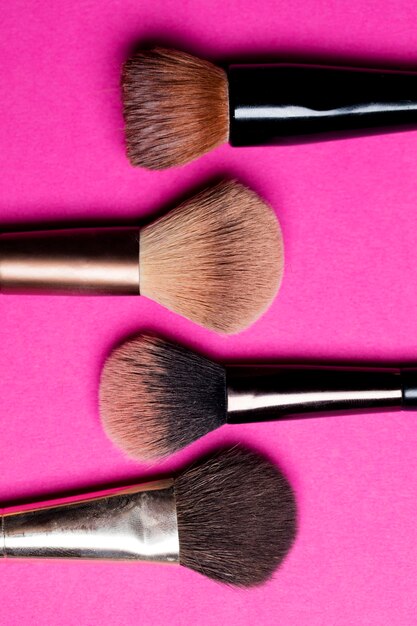 Makeup cosmetic blusher brushes on a pink background