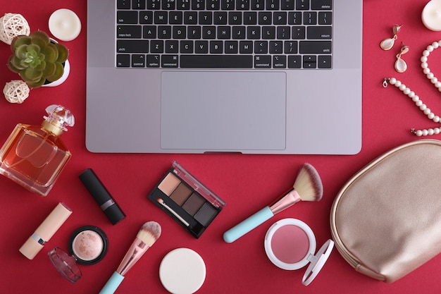 Photo makeup cosmetics and modern laptop on a colored background top view