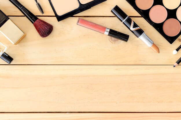 Makeup cosmetics on wooden table background with text space, over light, top view