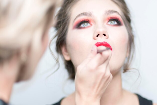 Makeup Makeup artist applies red lipstick Sensual lips Closeup