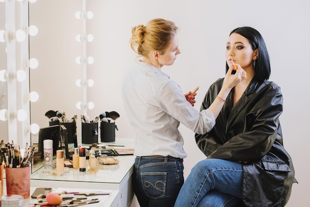 Makeup master doing makeup to beautiful model indoor beauty\
studio