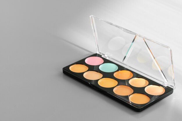 Makeup palette with colorful concealers on gray surface