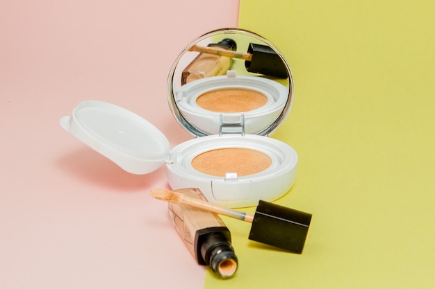 Makeup products on a bright yellow and pink background