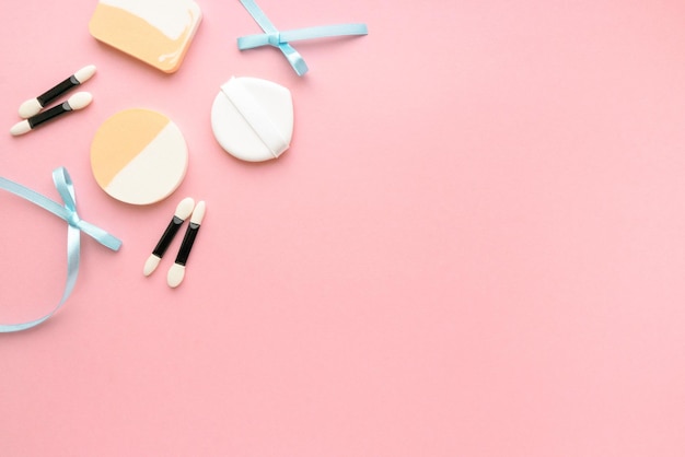 Photo makeup sponges and eyeshadow applicators on pink background space for text