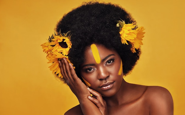 Foto trucco girasole e arte con ritratto di donna nera in studio per la bellezza creativa o primaverile cosmetici naturali e floreali con il volto della modella su sfondo giallo per bagliore amore per se stessi o fiducia