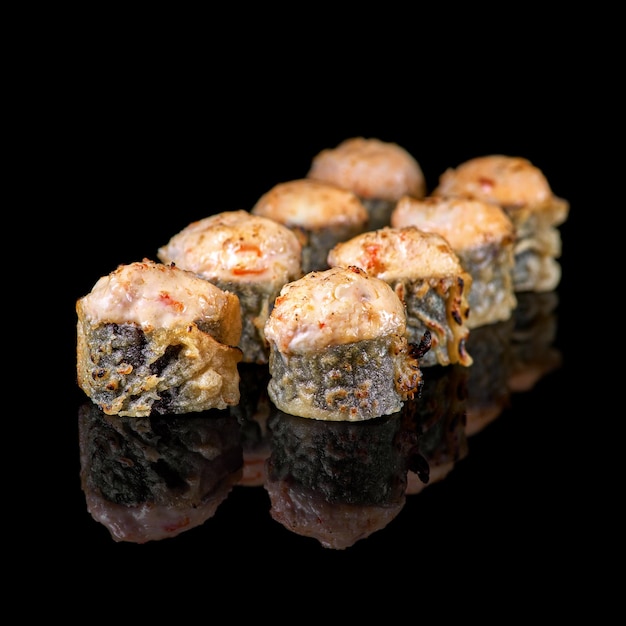 Maki fried hosomaki sushi with fresh salmon philadelphia cheese and teriyaki sauce on black background with reflection