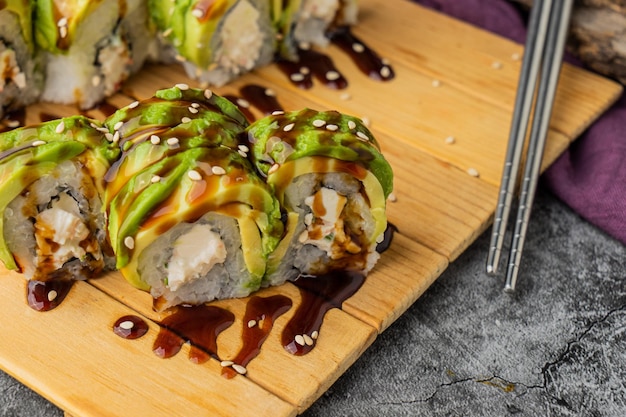 Maki roll with avocado and sesame outside,  cheese inside and sweet sauce