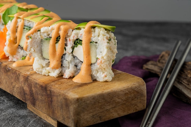 Maki roll with avocado and sesame outside,  cheese inside and sweet sauce