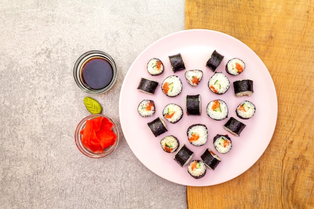 Maki rolletjes met gember, wasabi en sojasaus op een rosé bord