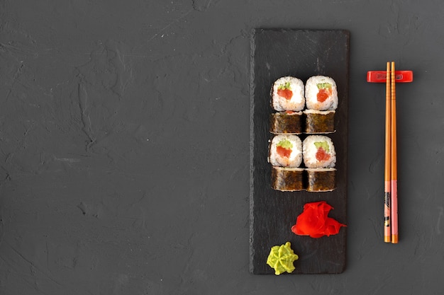 Maki sushi on black stone plate top view