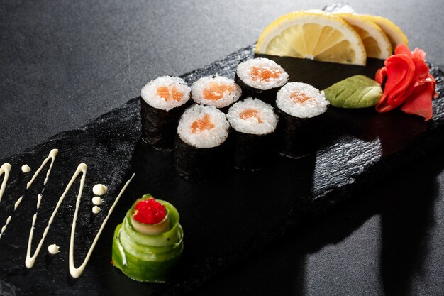 Maki Sushi Rolls met zalm op zwarte steen op dark