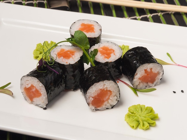 Involtini di sushi maki con salmone su un primo piano piatto bianco