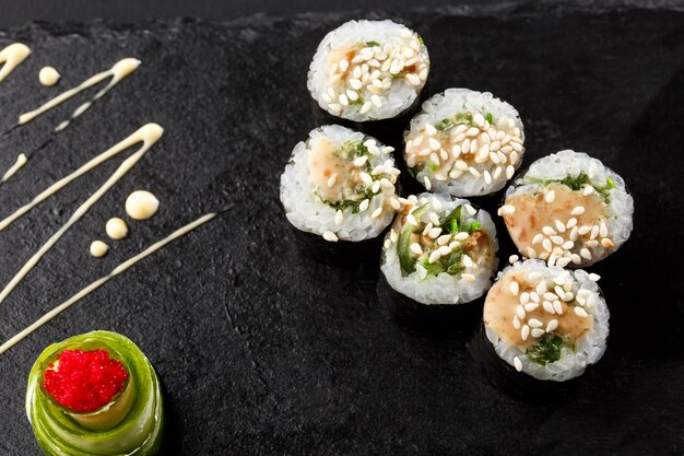 Maki Sushi Rolls with wakame and nut sauce on black stone on dark 