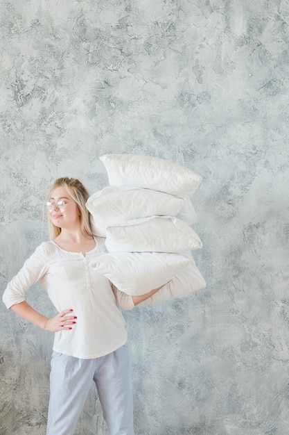 Making bed. Morning chores concept. Organized housewife holding pile of pillows easily.