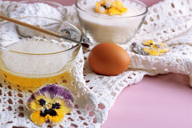 Making candied violet flowers with egg whites and sugar on color wooden background