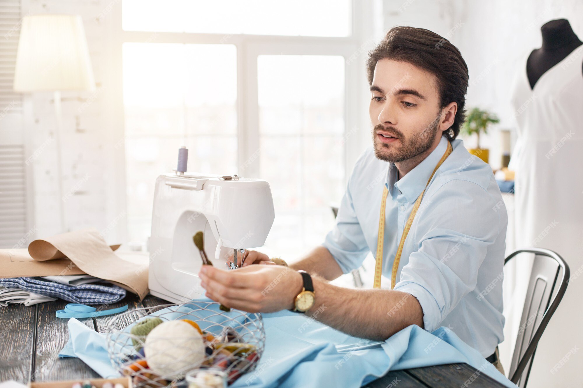 Premium Photo | Making clothes. determined dark-haired tailor smiling and working on a sewing machine