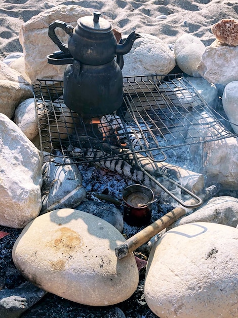 Making coffee on a sandy beach among the stones. Vintage teapot.