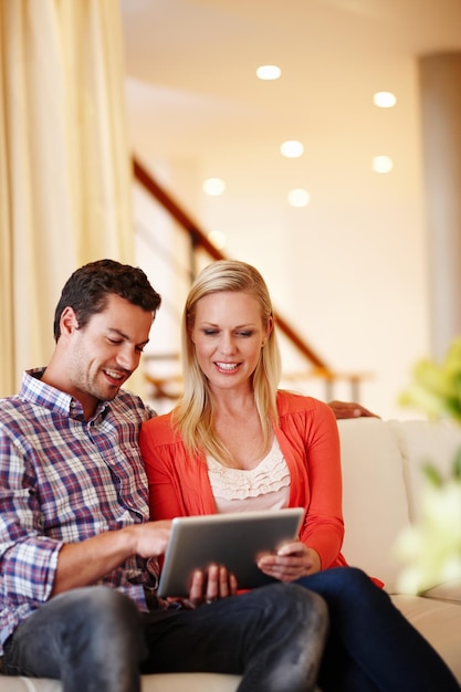 Making decisions as a team A happy couple sitting on their couch working on a digital tablet copyspace