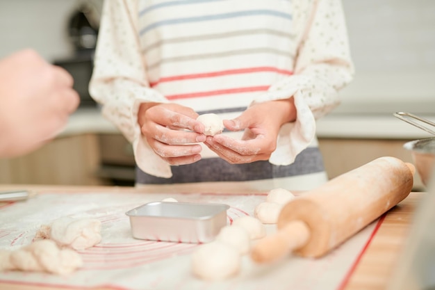 写真 木製のテーブルの背景に女性の手で生地を作る