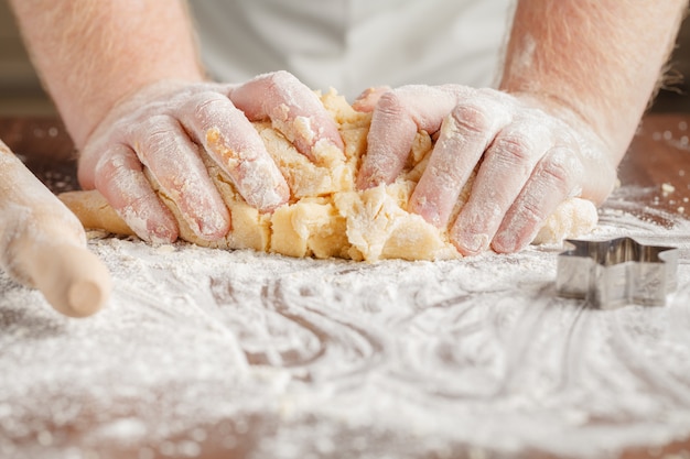 Making dough by mens hands on wooden table background