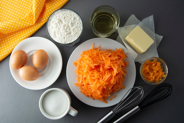  Making dough for carrot cake, pie, muffins or tart - eggs, flour, butter, orange, citrus, oil, sugar. Flat lay.