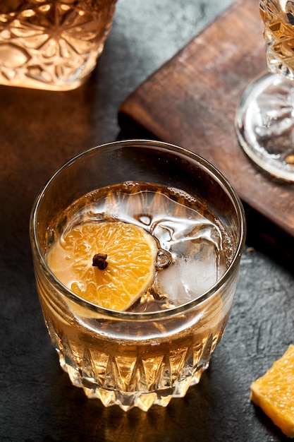 making drink with orange whiskey and honey, cocktail with fruit on rustic black base