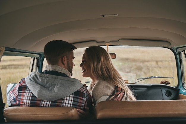 Making each other happy. Beautiful young couple bonding and smiling while sitting on the front passenger seats in retro style mini van