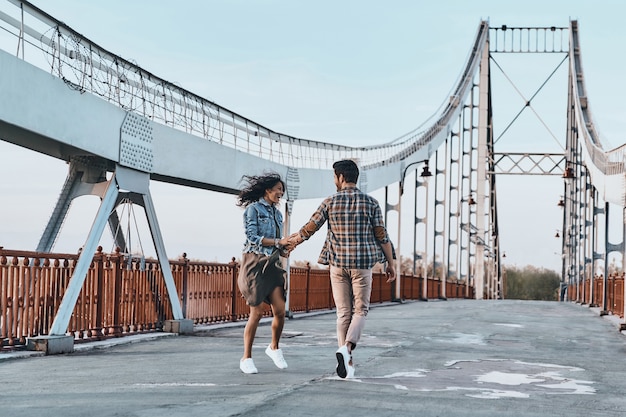 Making each other happy. Full length of playful young couple holding hands 