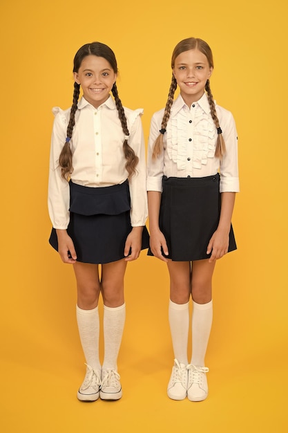 Photo making everything right excellent pupils girls perfect uniform outfit on yellow background according to school rules classmates tidy pupils educational program for gifted kids best pupils award