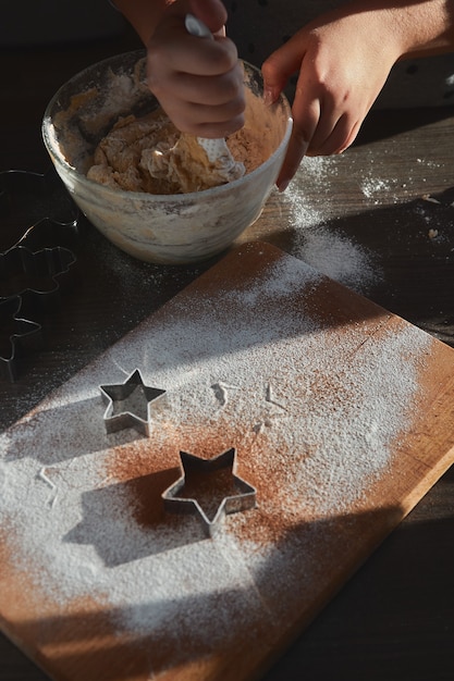 Preparare l'impasto per biscotti allo zenzero. le mani di una giovane donna si mescolano in una lastra di vetro per cuocere la pasta degli uomini di pan di zenzero. il concetto di una festa in casa, una cena in famiglia.