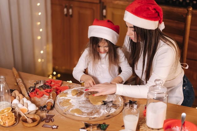 Making gingerbread at home little girl cutting cookies of gingerbread dough christmas and new year