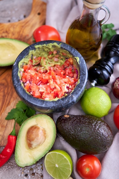 Making guacamole crushed avocado in marble mortar and\
ingredients