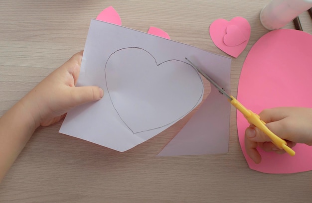 Foto realizzare biglietti di auguri di san valentino fatti a mano. artigianato per bambini, concetto di hobby, regalo con le tue mani. decorazione per san valentino, festa della mamma. passaggio 1. messa a fuoco selettiva.