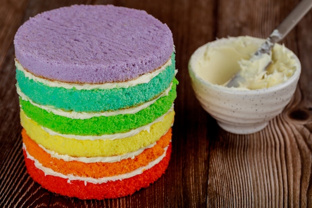 Making homemade rainbow cake with white cream and knife.