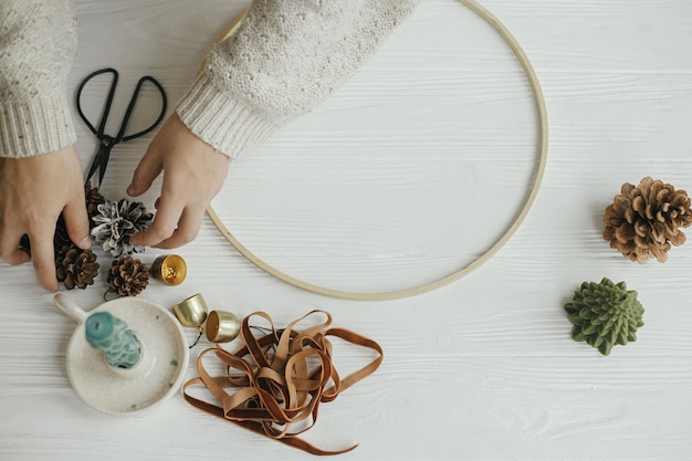 Making modern christmas wreath top view Woman hands with round hoop ribbon candle