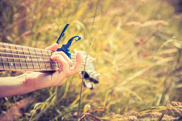 Making music outdoors Young man plays the guitar close up