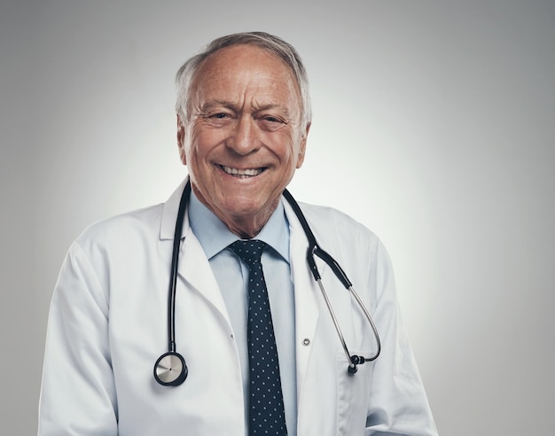 Making my way through the hospital shot of a happy elderly male doctor in the studio against a grey