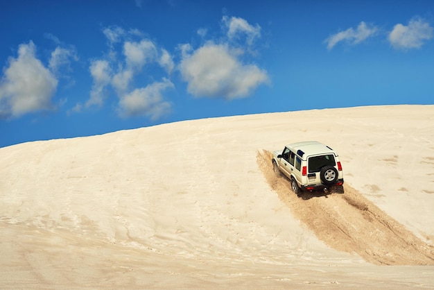 新しい道路を作るいくつかの砂丘に沿って運転する頑丈な4x4のショット